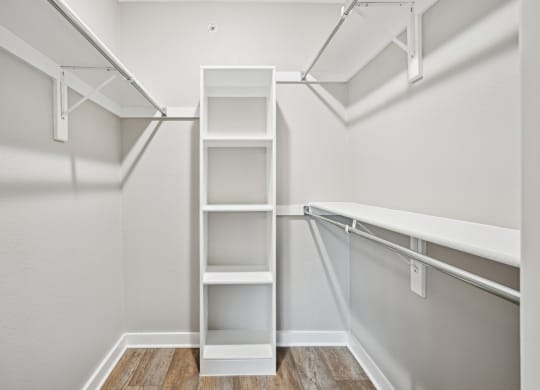 A spacious walk in closet with white shelves at Windridge On The Parkway Apartments in Dallas, TX