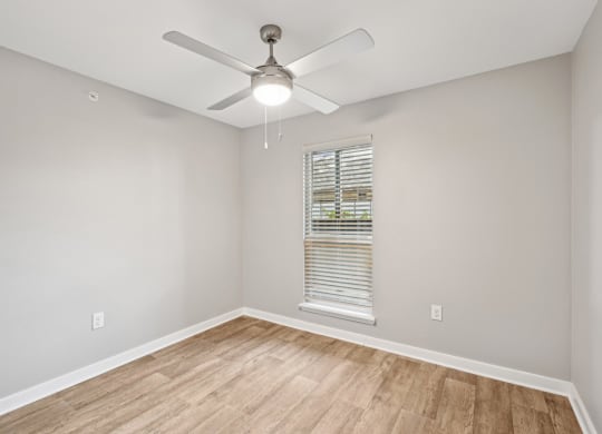 an empty room with a ceiling fan and a window