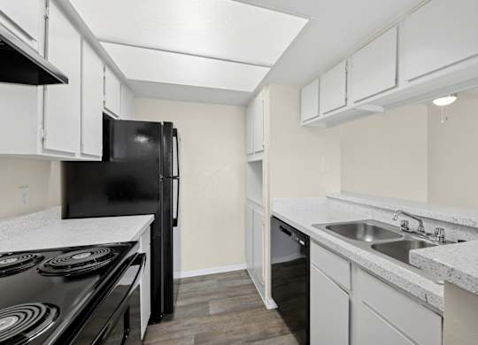 A kitchen with black appliances and white cabinets at Westdale Pointe in Austin, TX