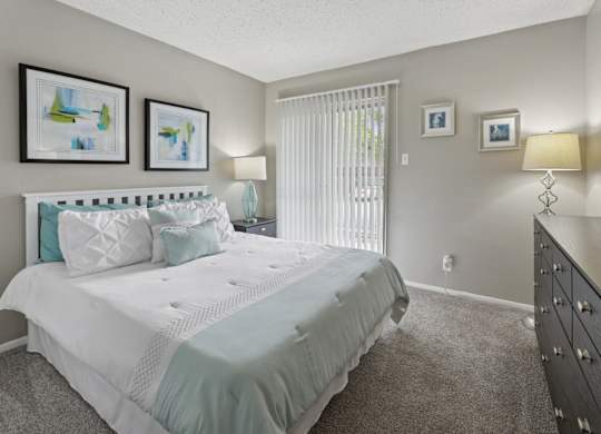 B1 bedroom with white bed and floor to ceiling sliding door at Westdale Pointe in Austin, TX