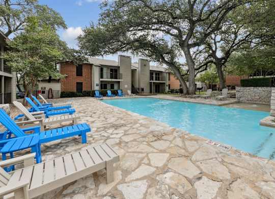 A pool surrounded by blue and white lounge chairs at Westdale Pointe in Austin, TX
