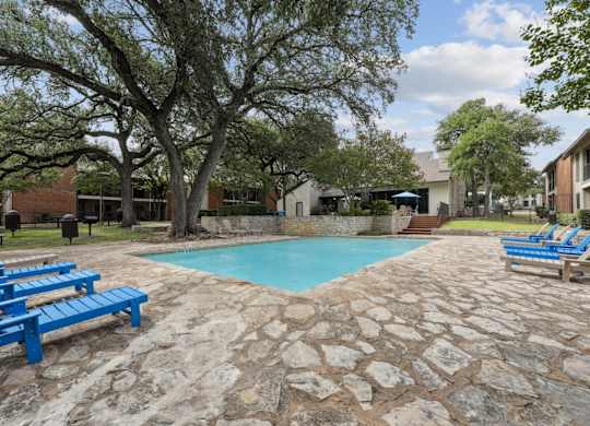 A pool surrounded by trees and chairs.