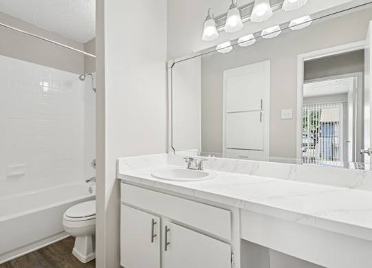 A5 bathroom with a toilet, sink, and mirror at Windridge on the Parkway apartments in Dallas, TX