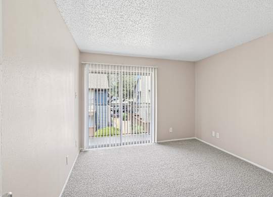 A5 bedroom with a carpeted floor and a sliding glass door leading to a balcony at Windridge on the Parkway in Dallas, TX