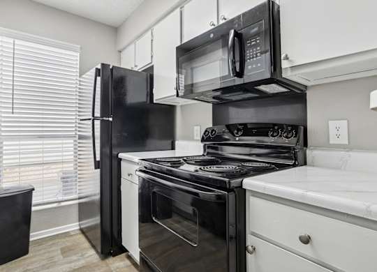 A6 kitchen with black appliances and white cabinets Windridge on the Parkway apartments in Dallas, TX.