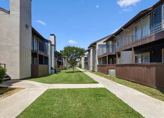 An area of grass and sidewalks between apartment buildings at Windridge on the Parkway in Dallas, TX