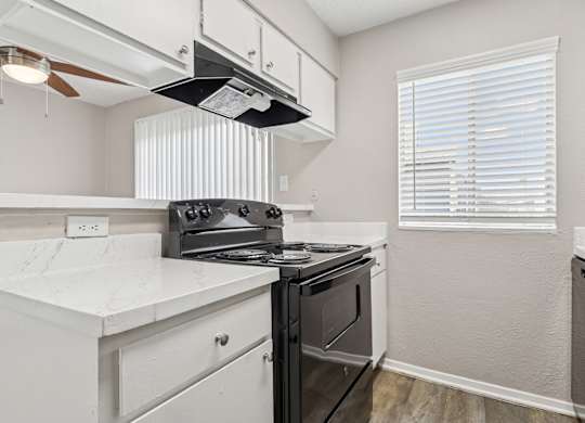 B6 kitchen with a black stove top oven and white cabinets at Windridge on the Parkway in Dallas, TX