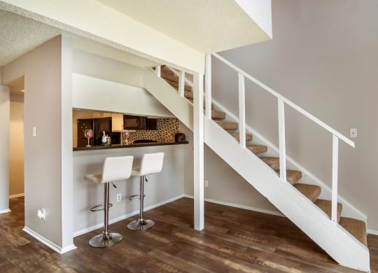 a bar under the stairs in a home with wood floors