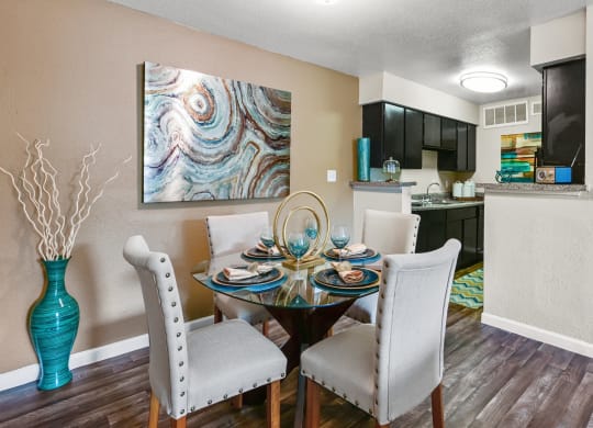 a dining room with a table and chairs and a kitchen in the background