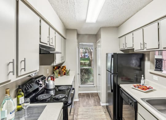 Model apartment kitchen with black appliances at Hunters Chase in Austin, TX