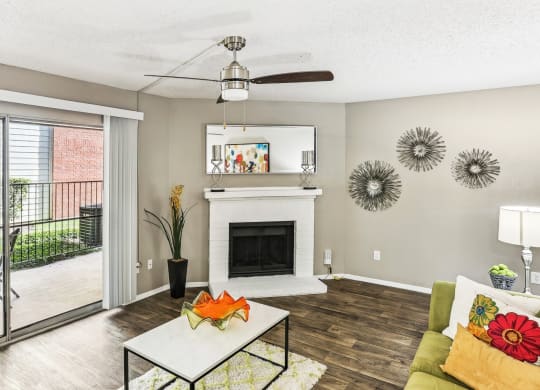 Model living room with a fireplace and a sliding glass door to patio at Hunters Chase in Austin, TX