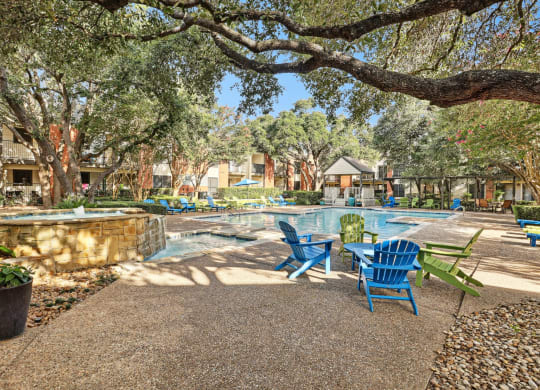 Swimming pool with blue chairs and trees at Hunters Chase in Austin, TX
