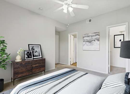 A carpeted bedroom in the B1 floorplan with a closet and connected bathroom at Jefferson Creek Apartments in Irving, TX
