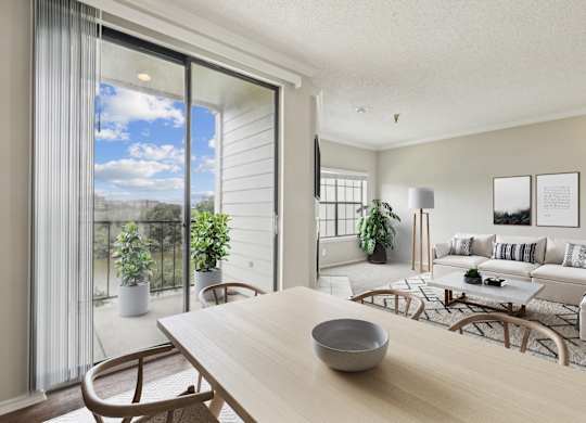 A modern living room  in the A2 floorplan with a wooden table and chairs and a glass sliding door leading to the balcony at Jefferson Creek Apartments in Irving, TX