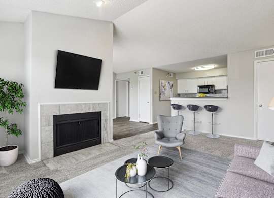 A living room in the A3 floorplan with white walls, a stone fireplace, and a grey couch at Jefferson Creek Apartments in Irving, TX