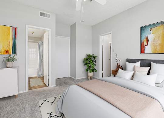 A bedroom in the B1 floorplan with a large bed and a painting on the white wall at Jefferson Creek Apartments in Irving, TX