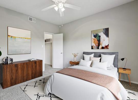 A carpeted bedroom with a large bed, ceiling fan, and a wooden dresser at Jefferson Creek Apartments in Irving, TX