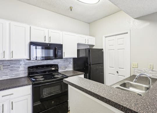 A1 floor plan kitchen with black appliances and elevated counter at Jefferson Creek Apartments in Irving, TX.