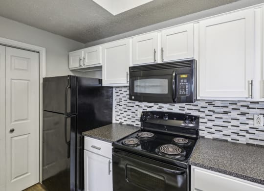 B1 floor plan kitchen with black appliances and white cabinets at Jefferson Creek Apartments in Irving, TX.