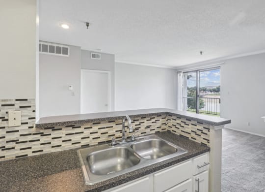 B1 floor plan kitchen sink area with elevated counter overlooking living room at Jefferson Creek Apartments in Irving, TX.