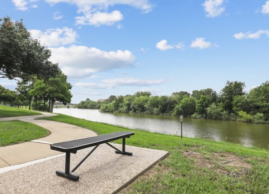 a bench sitting next to a river at Jefferson Creek in Irving, TX