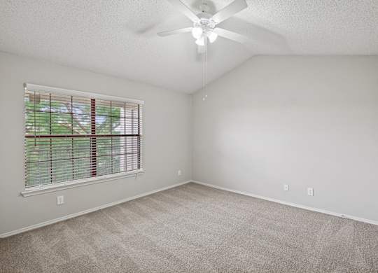 B1 bedroom with a ceiling fan, white walls, and a window at Jefferson Place Apartments in Irving, TX