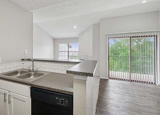 B2 kitchen overlooking living room and sliding door to private balcony at Jefferson Place apartments in Irving, TX