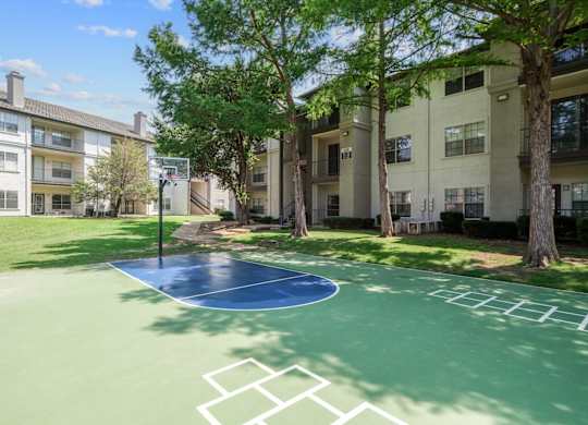 A basketball court and hopscotch area surrounded by apartment buildings at Jefferson Place Apartments in Irving, TX