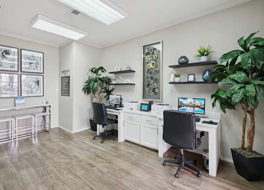 A business center with computers, printers, and potted plants at Jefferson Place Apartments in Irving, TX
