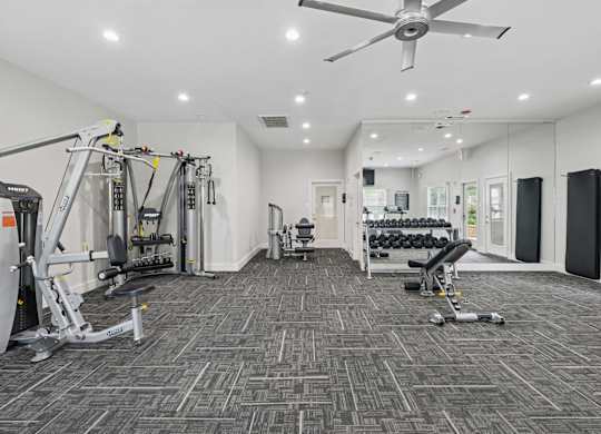 A spacious fitness center with a variety of equipment including treadmills and strength training machines at Jefferson Place Apartments in Irving, TX