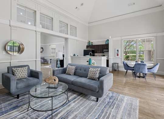 Resident lounge with grey couches, a glass coffee table, and a gray rug at Jefferson Place Apartments in Irving, TX