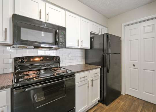 B2 kitchen with black appliances and white cabinets at Jefferson Place Apartments in Irving, TX