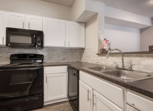 a kitchen with white cabinets and black appliances