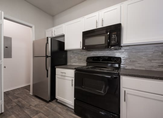 a kitchen with white cabinets and black appliances
