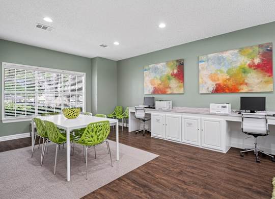 Business center room in the leasing office with a white desk and green chairs.
