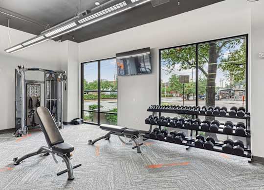 Free weights and workout benches in our state-of-the-art fitness center at Muse at Museum District apartments in Houston, TX
