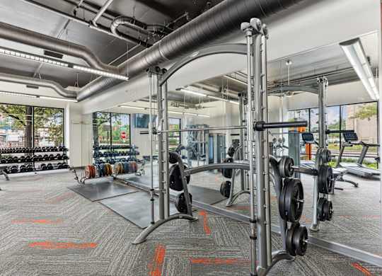 Our gym with a variety of equipment including dumbbells and weight plates at Muse at Museum District apartments in Houston, TX