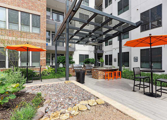Outdoor grilling station under a pergola with two bbq grills at Muse at Museum District apartments in Houston, TX
