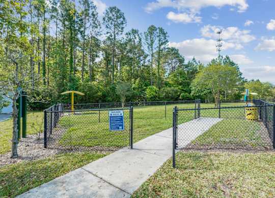 A sign is on a fence in front of a grassy area.