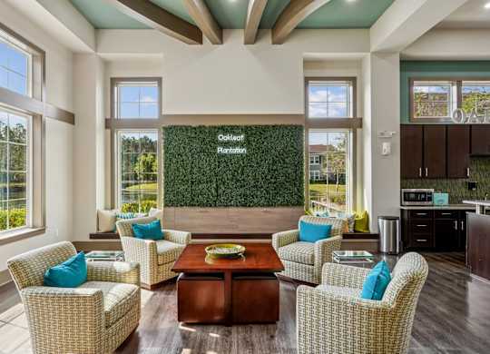 A clubhouse with a decorative grass wall and an Oakleaf Plantation sign surrounded by comfortable chairs and a table at Oakleaf Plantation Apartments in Jacksonville, FL