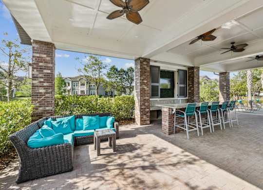 A patio with a couch, chairs, and a table under a roof.
