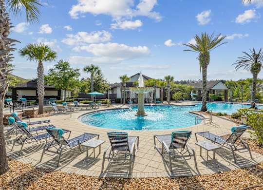 A pool surrounded by palm trees and lounge chairs.