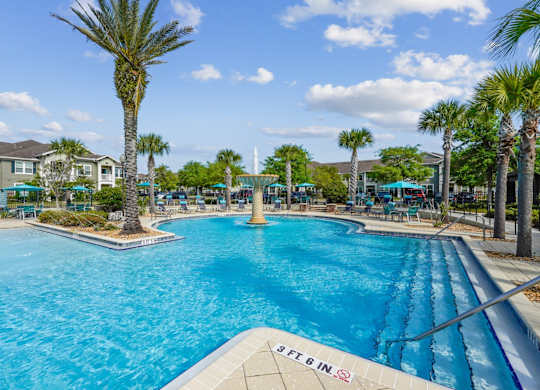 A large pool with a slide and palm trees around it.
