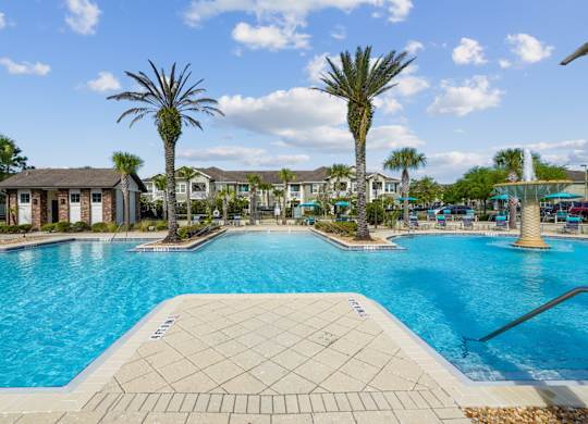 A large swimming pool surrounded by palm trees and residential buildings.