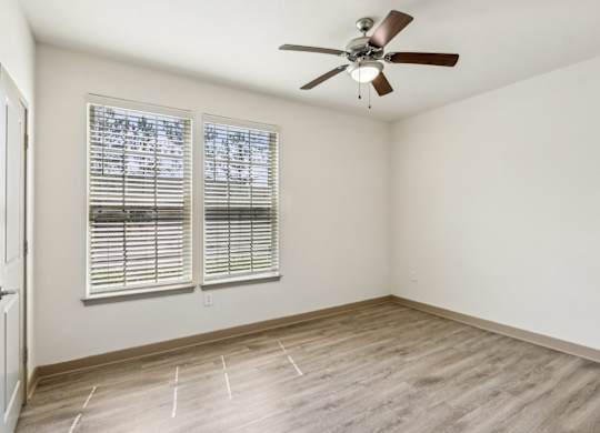A room with a ceiling fan and a window with blinds.
