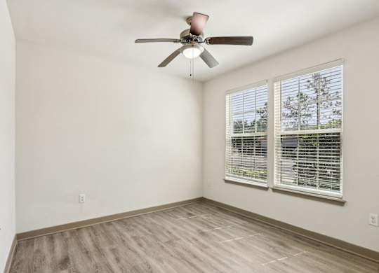A room with a ceiling fan and a window with blinds.