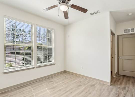 A room with a ceiling fan and a door leading to another room.