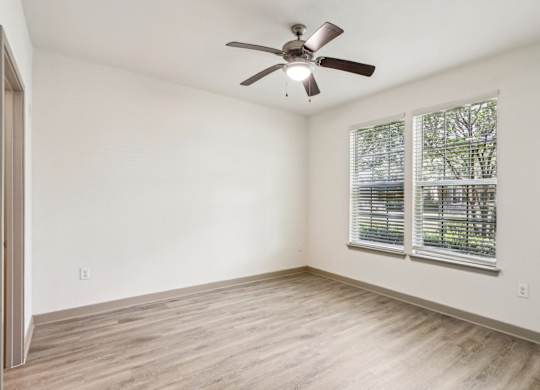 Royal Palm floor plan bedroom with a ceiling fan and a window with blinds at Oakleaf Plantation apartments in Jacksonville, FL.