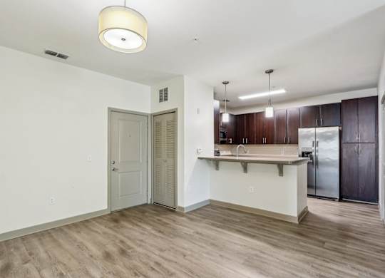 Royal Palm kitchen area with white walls, dark wood cabinets, and a wooden floor at Oakleaf Plantation Apartments in Jacksonville, FL
