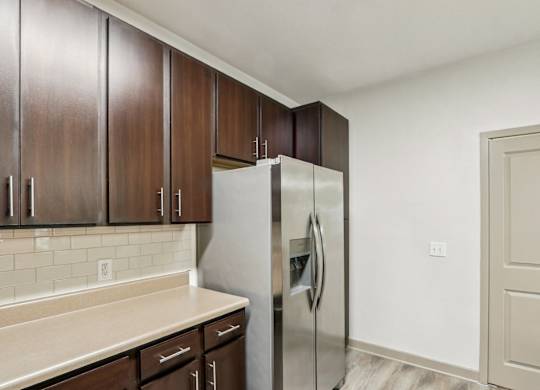 Royal Palm kitchen with brown cabinets and a stainless steel refrigerator at Oakleaf Plantation apartments in Jacksonville, FL.